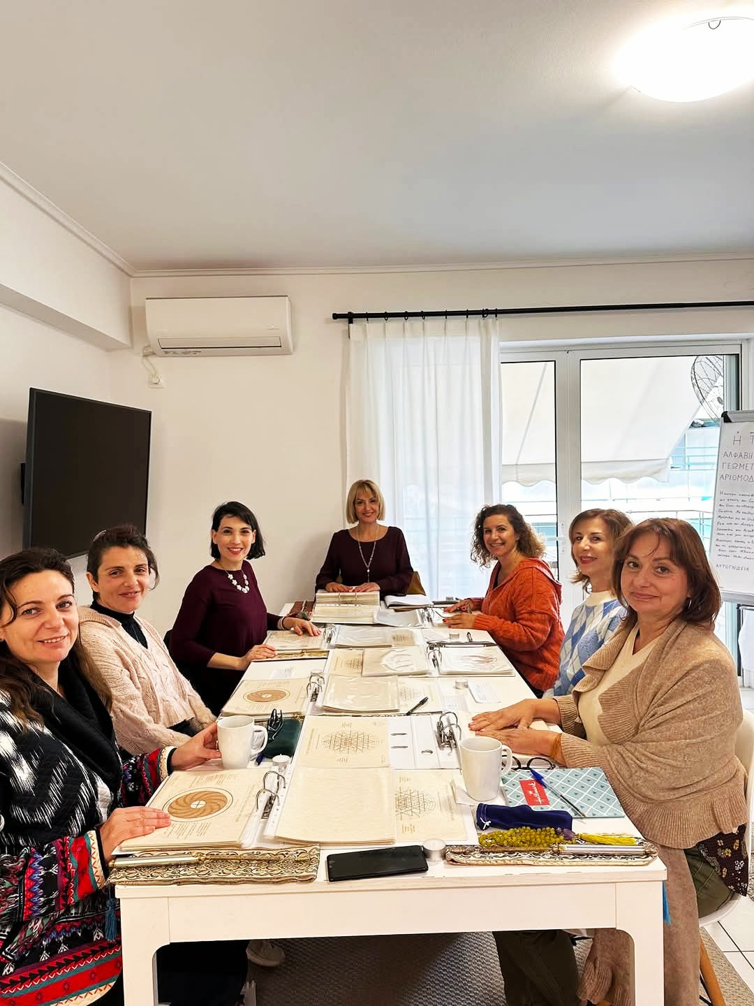 Art of Iasis Workshop – Anagennisi Academy seminar of self-knowledge and spiritual growth. Group of women sitting around a table in a classroom setting