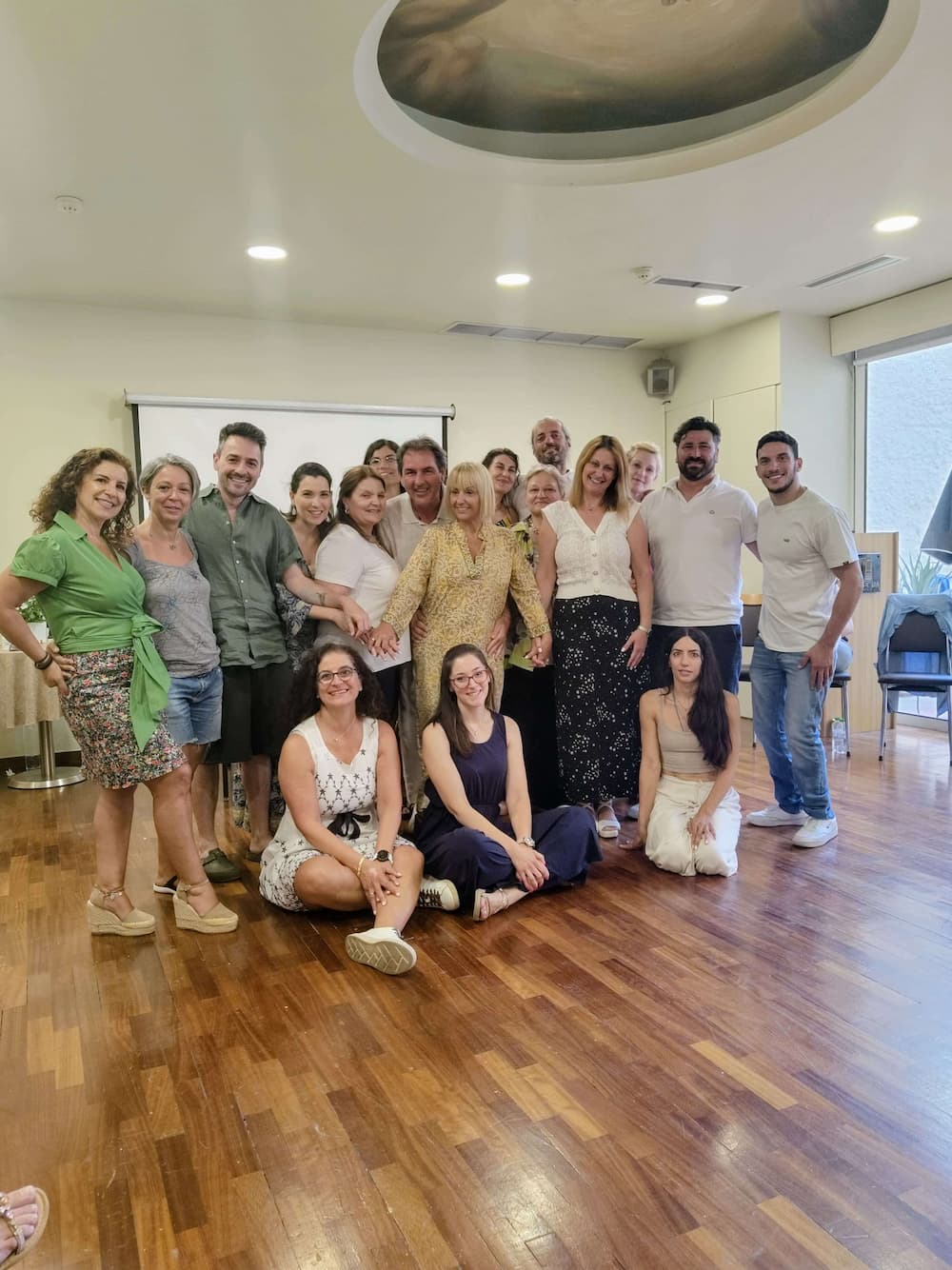 Systemic Soul Healing. Group of people posing for a photo in a room with wooden flooring and a large window.