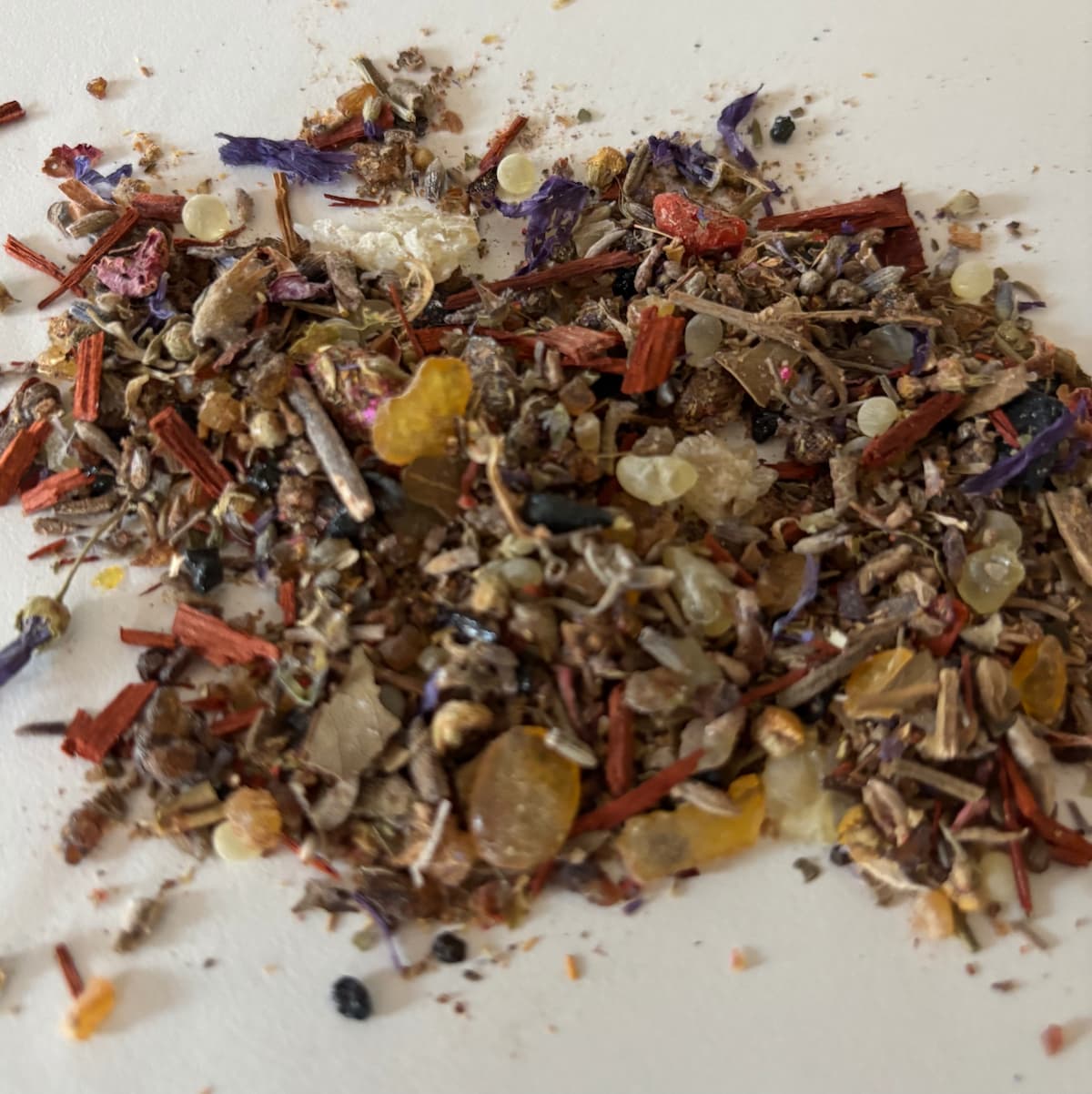 Close-up of AnaGennisi ritual energy incense blend with natural resins, purifying herbs, aromatic woods, essential oils, and crystal vibrations.