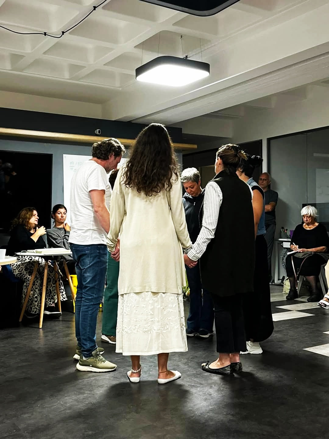 Systemic Soul Healing. Group of people in a room with one person in a white dress standing out